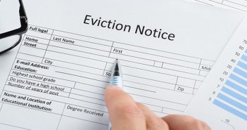 4 Frequently Asked Questions on Evicting a Tenant Close-up Of Hand With Pen And Eyeglasses Over Eviction Notice Paper
