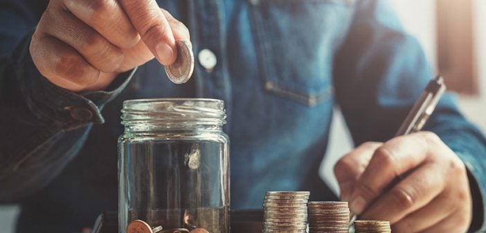 hand puting coins into jug glass for saving money finance and accounting concept