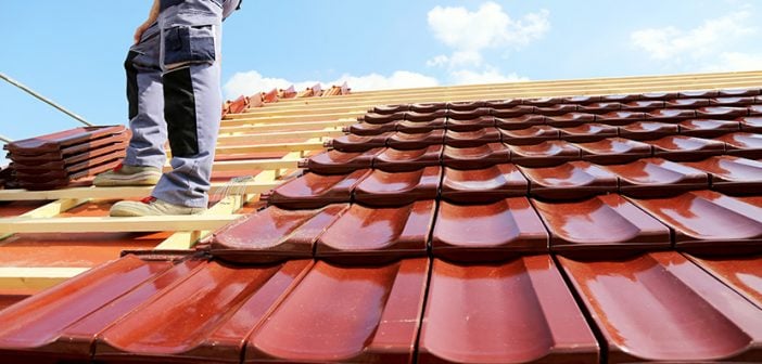 worker standing on roof installing new tiles