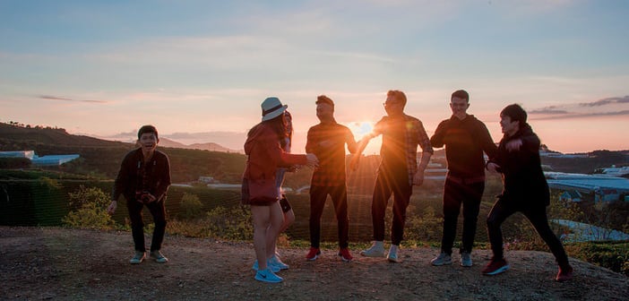 group of young adults outside looking at a sunset