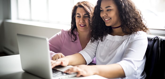 A Mother And Teenage Daughter Looking At Laptop Together