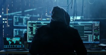 Should Homeowners Insurance Cover Cyber Fraud? Dangerous Hooded Hacker Breaks into Government Data Servers and Infects Their System with a Virus. His Hideout Place has Dark Atmosphere, Multiple Displays, Cables Everywhere.