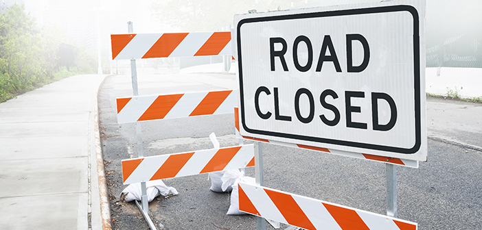 Dusty road closed sign on a city road, background