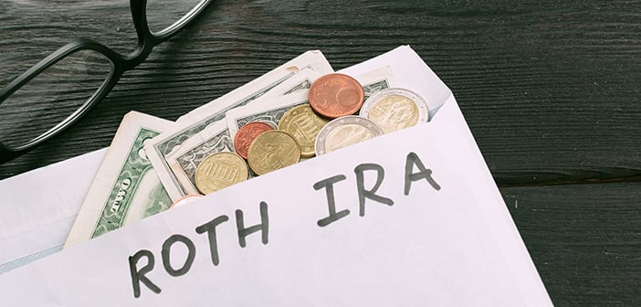 envelope with cash and change falling out labeled Roth IRA in permanent marker with glasses on a desktop