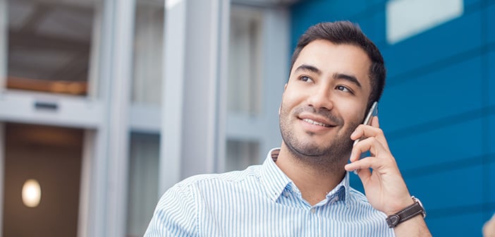 Happy young man on phone, indoors - inside. Close up of businessman talking on mobile phone - smartphone. Comunicative friendly hispanic man