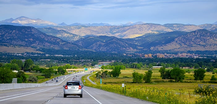 car driving down interstate 36 in Colorado toward the city of Boulder with mountains in distance