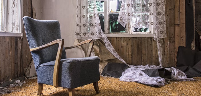 disheveled living room with broken window fluttering curtains blue apholstered chair