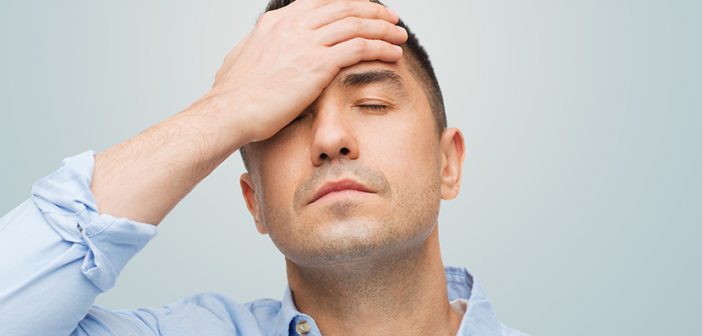 unhappy man with closed eyes touching his forehead