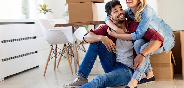 Young couple in love unpacking cardboard boxes at new home moving in concept