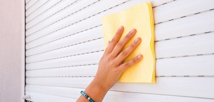 young woman cleaning sunblind on white pvc window