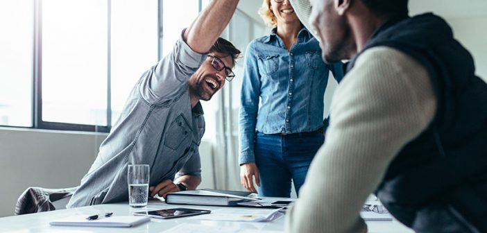 Two colleagues giving high five in meeting. Business people celebrating success in conference room.
