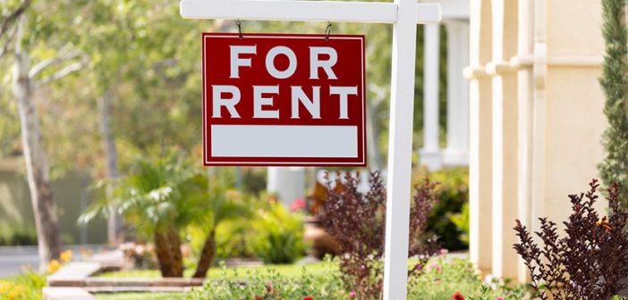red for rent sign in front yard of home in nicely landscaped neighborhood