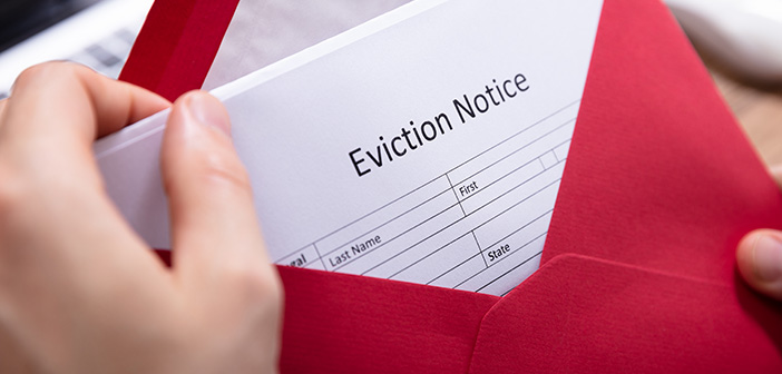 Close-up Of A Person's Hand Holding Eviction Notice In Red Envelope