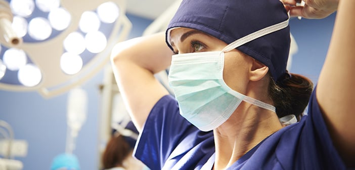 Side view of young female surgeon tying her surgical mask