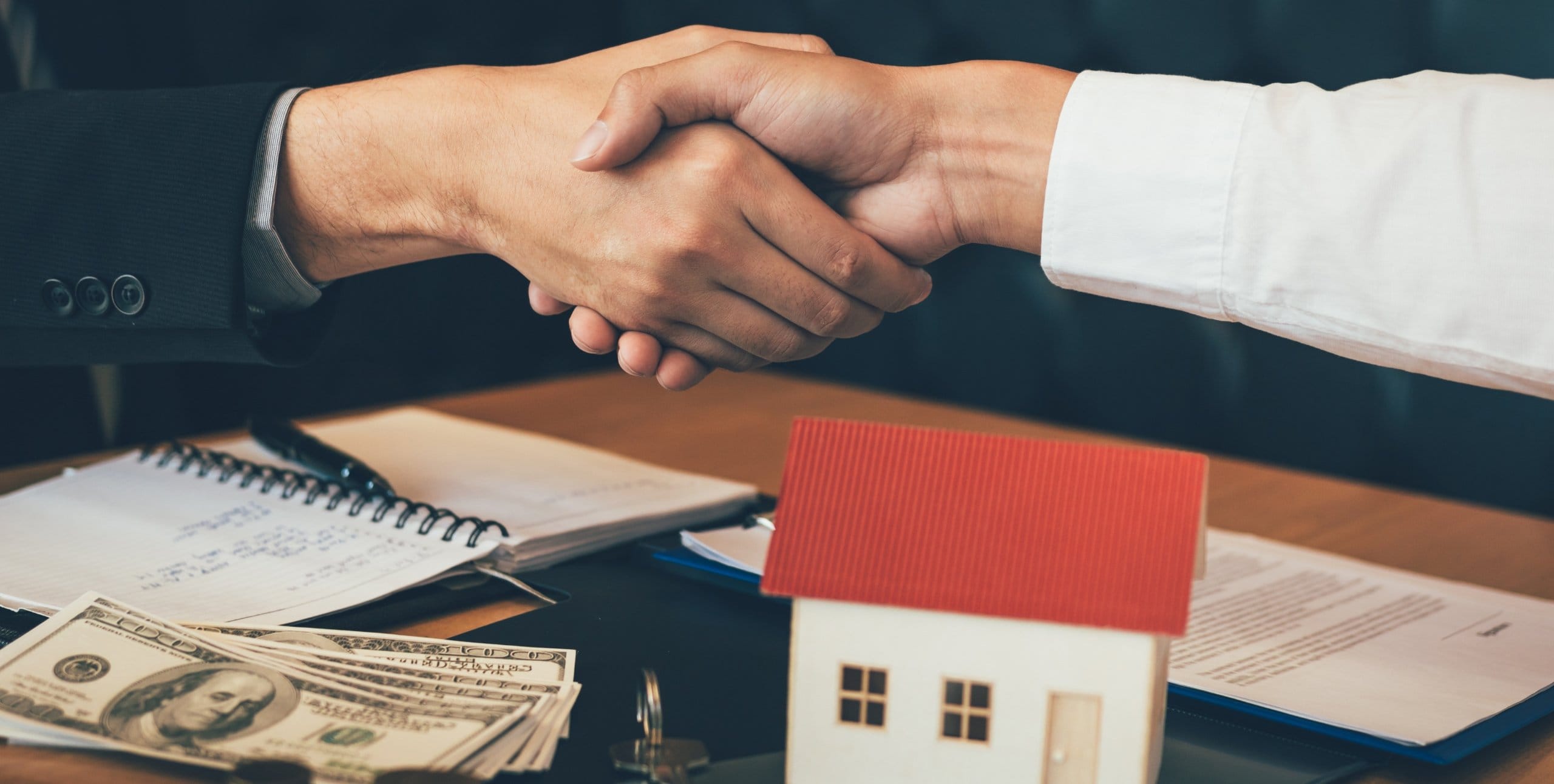 shaking hands over a small house