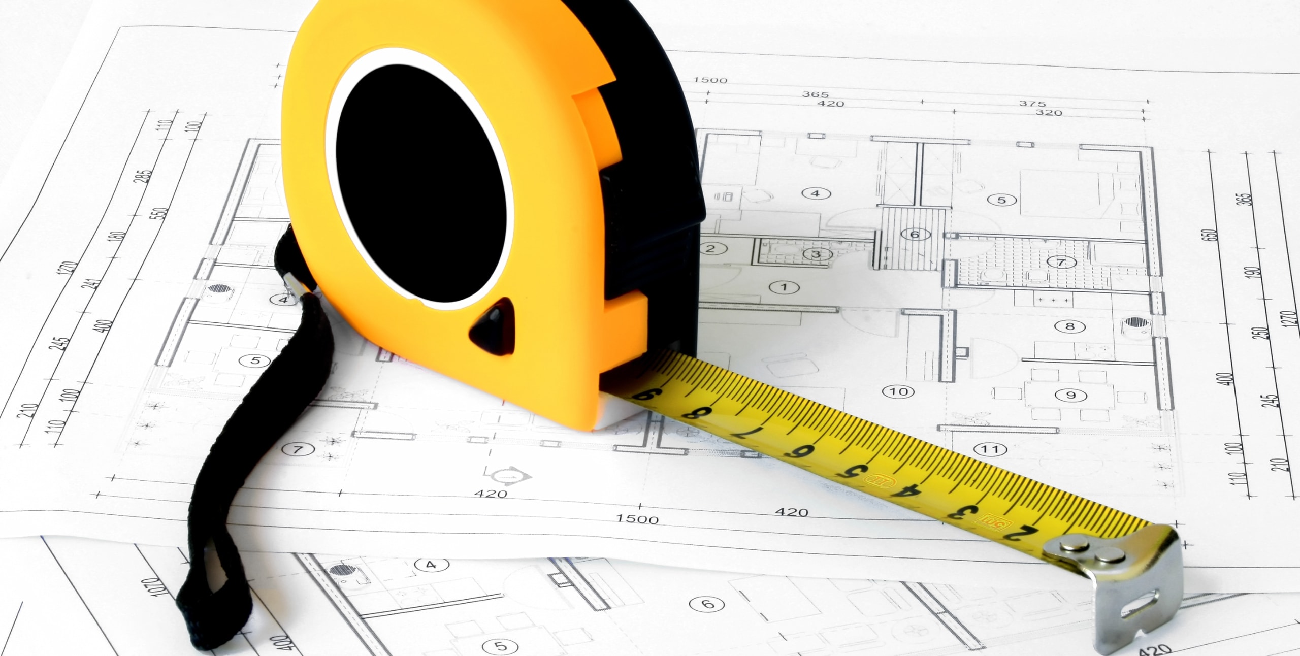 measuring tape on top of blueprints