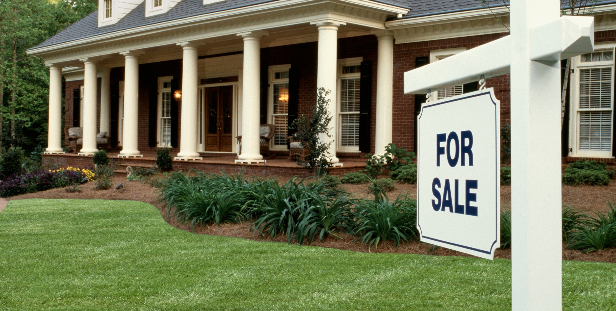 for sale sign placed in front of brick house