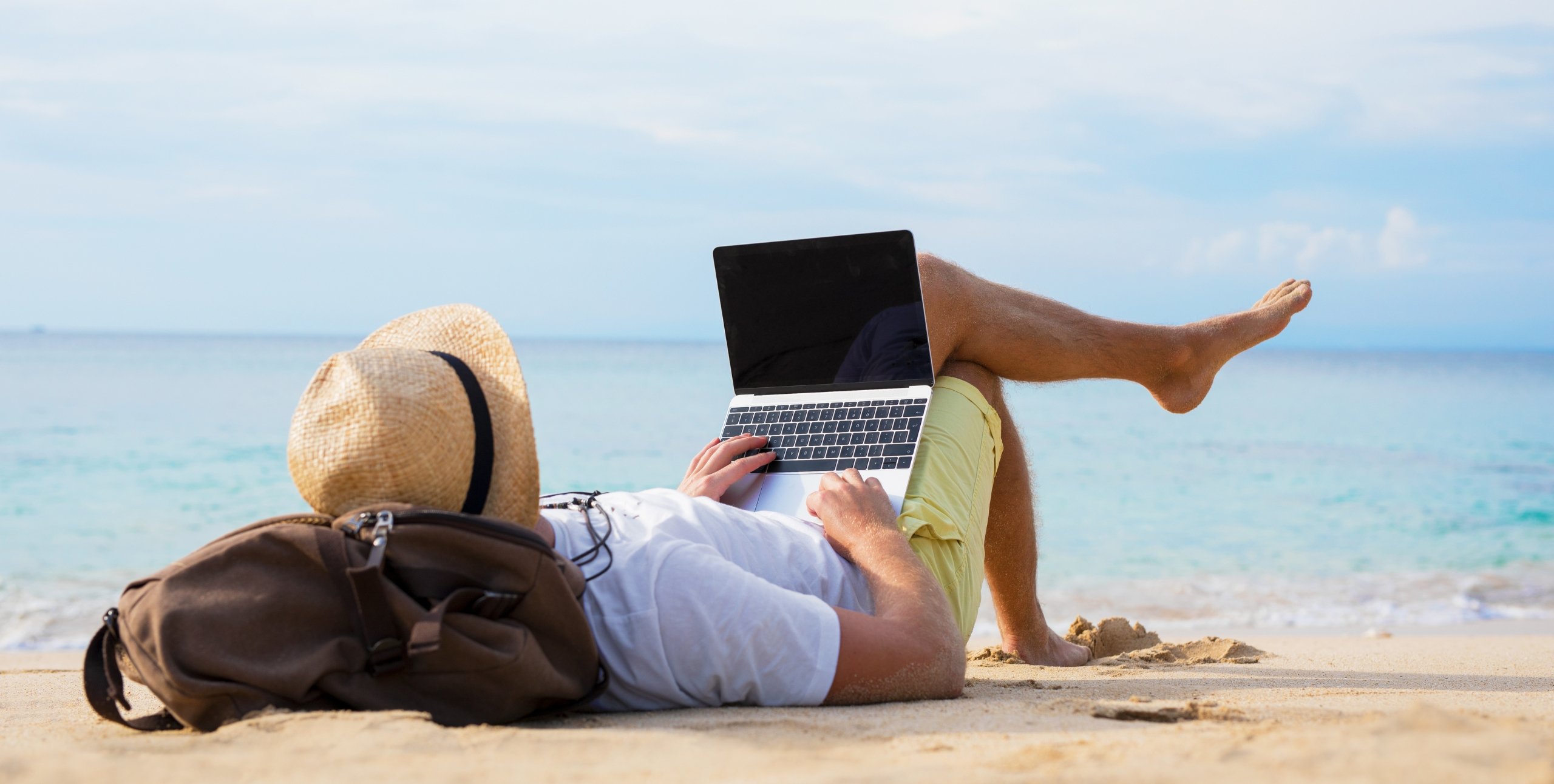 man working on beach with laptop