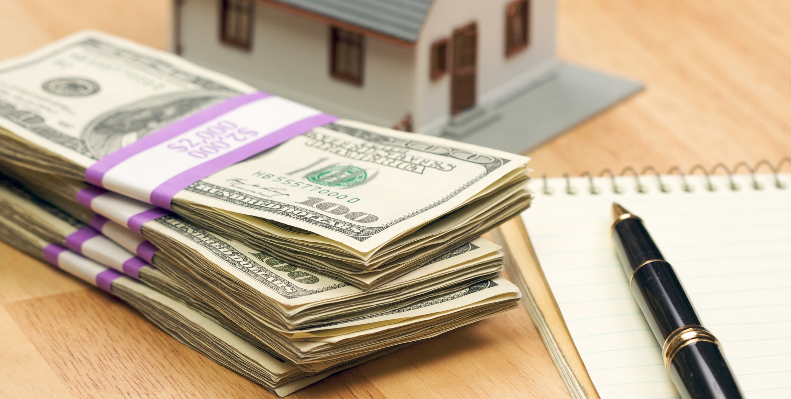 stack of cash next to a small house