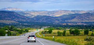 car driving down interstate 36 in Colorado toward the city of Boulder with mountains in distance